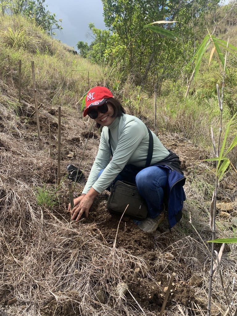 USTP Panaon Acting Director poses while planting a seedling